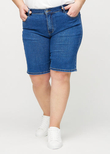 Mörk denim regular middle shorts, modellnamn Oceans, som går rakt ner längs benet och slutar precis ovanför knät på en plus-size-modell, sedd framifrån.