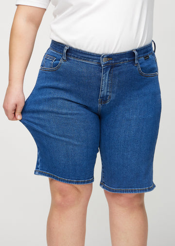 Plus-size-modellen drar ut shortsen vid låret för att visa stretch.