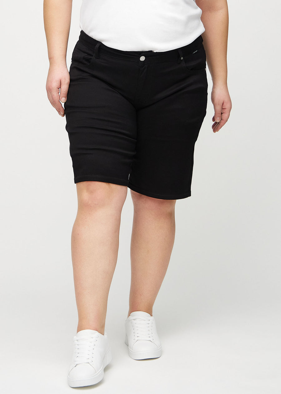 Svarta regular middle shorts, modellnamn Ravens, som går rakt ner längs benet och slutar precis ovanför knät på en plus-size-modell, framifrån.
