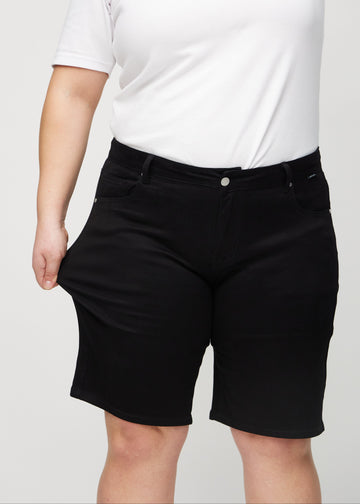 Plus-size-modellen sträcker ut shortsen vid låret för att visa stretch.