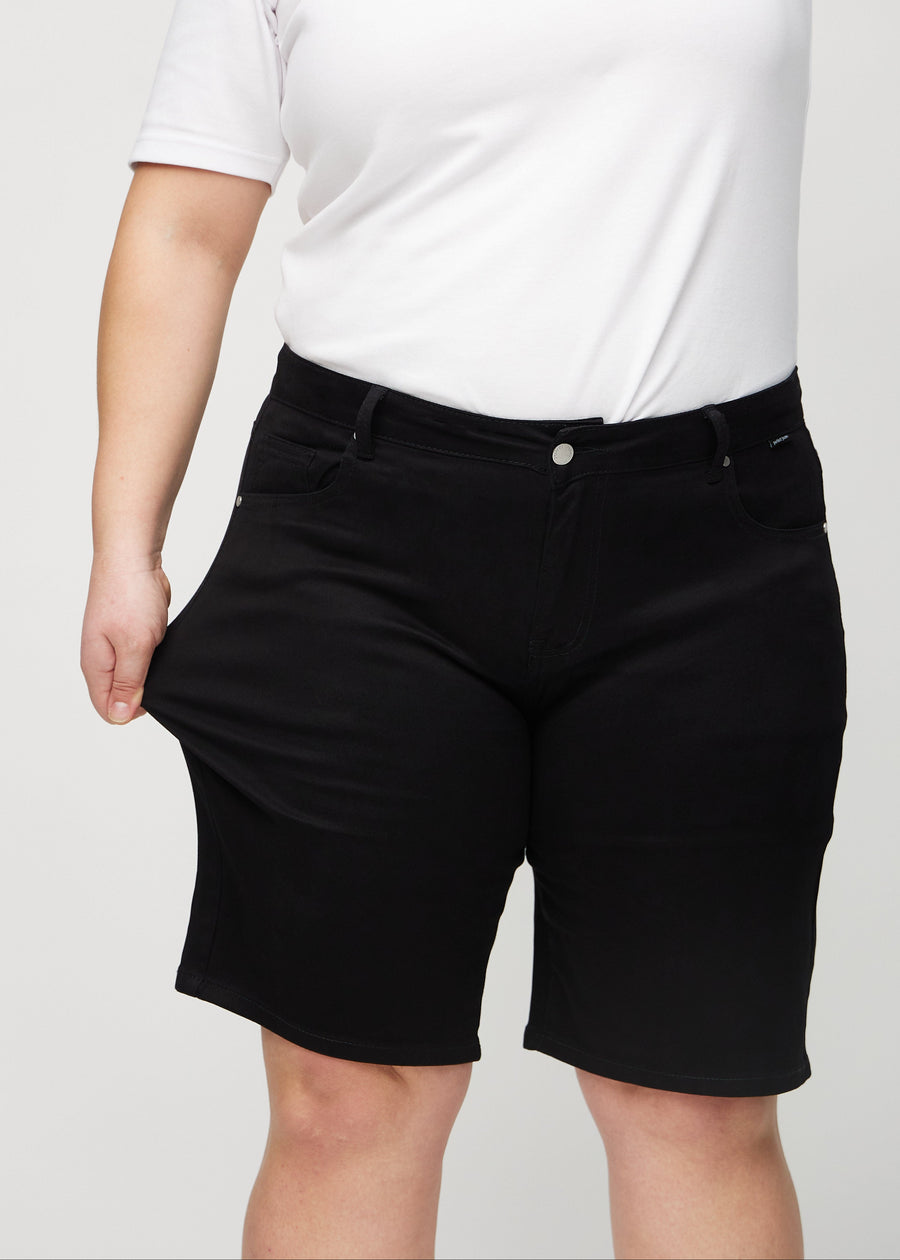Plus-size-modellen sträcker ut shortsen vid låret för att visa stretch.