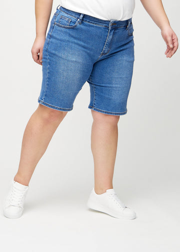 Denim regular middle shorts, modellnamn Rivers, som går rakt ner längs benet och slutar precis ovanför knät på en plus-size-modell, sedd framifrån.