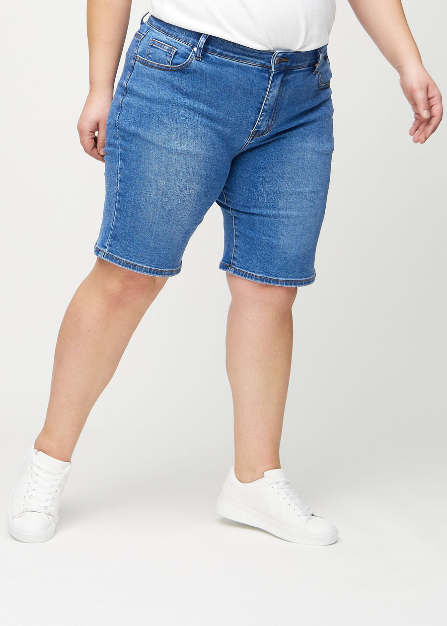 Denim regular middle shorts, modellnamn Rivers, som går rakt ner längs benet och slutar precis ovanför knät på en plus-size-modell, sedd framifrån.
