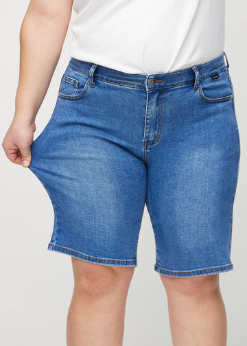 Plus-size-modellen sträcker shortsen vid låret för att visa stretch.