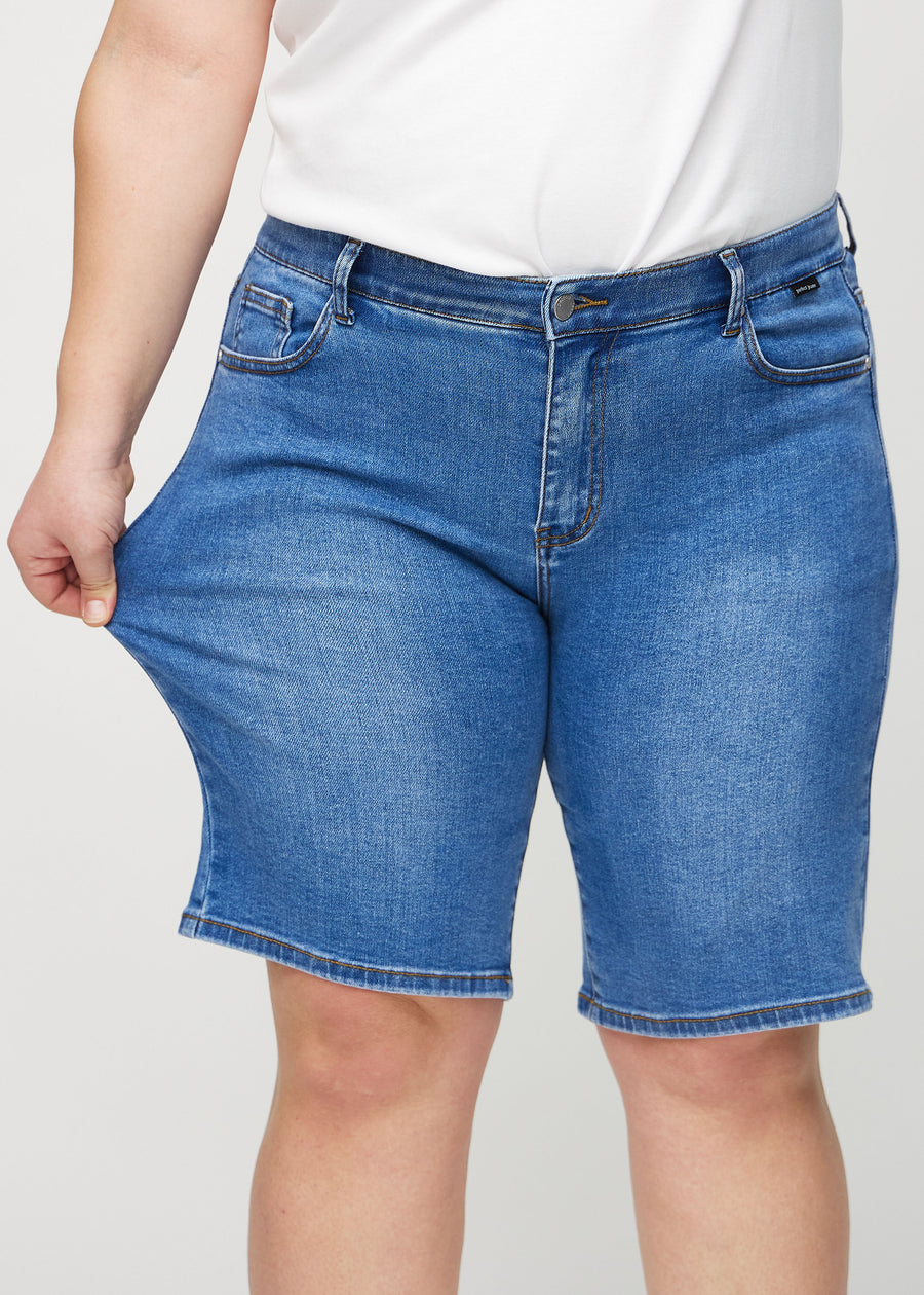 Plus-size-modellen sträcker shortsen vid låret för att visa stretch.