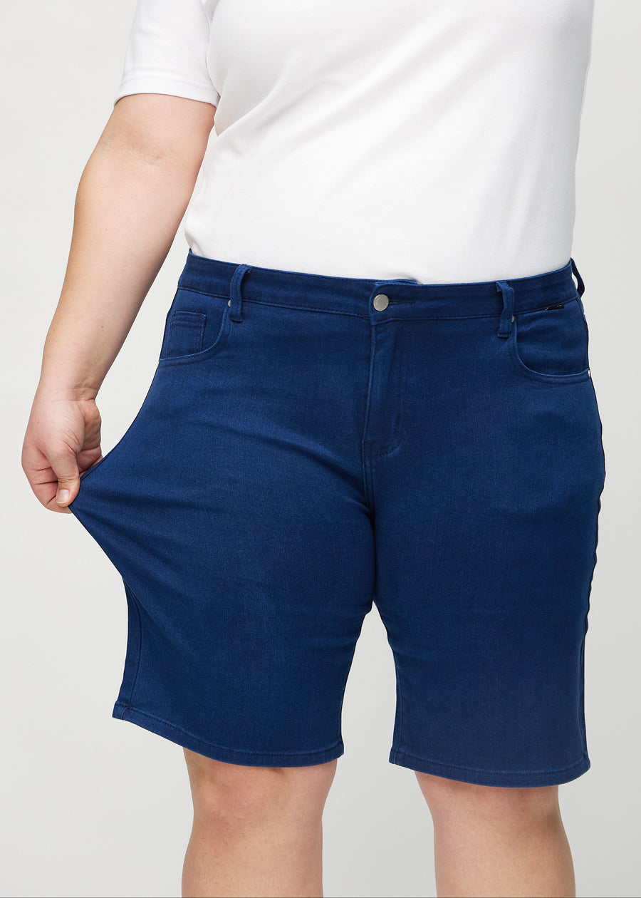 Plus size-modellen sträcker shortsen vid låret för att visa stretch.