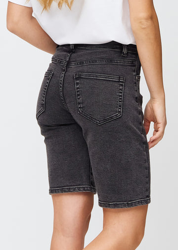 Kvinna i knälånga mörkgrå denimshorts sedd bakifrån, så att man kan se denimdetaljerna
