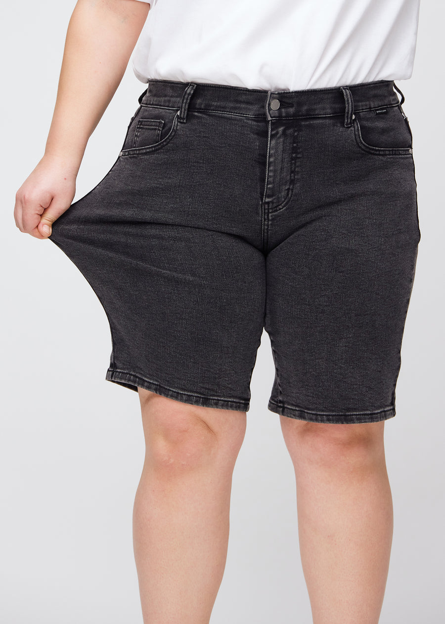 Plus-size-modell stretchar shortsen vid låret för att visa stretch.