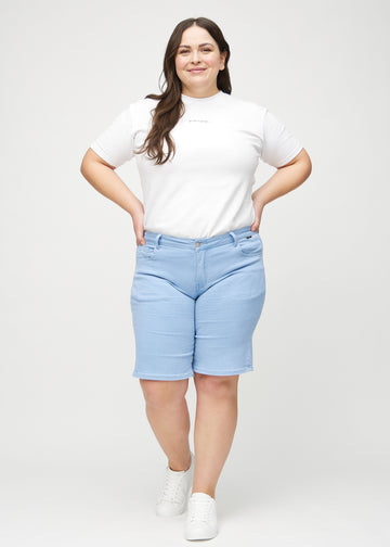 Helbild av en plus size-modell i ljusblå regular middle shorts.
