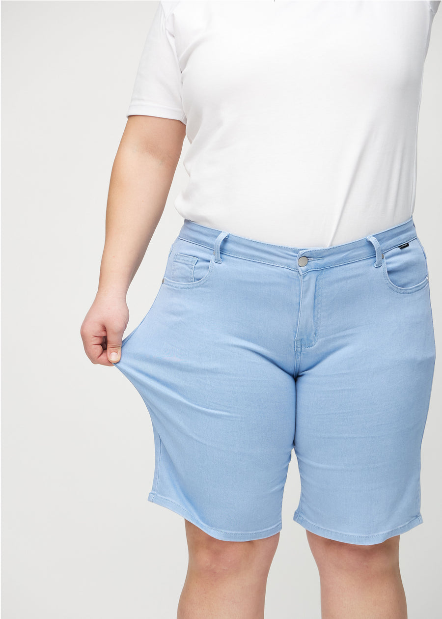 Plus size-modellen sträcker shortsens lårparti för att visa stretch.
