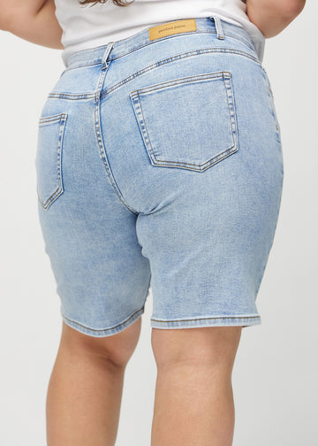 Ljus denim regular middle shorts sedd bakifrån på nära håll på en plus-size-modell för att visa detaljer.