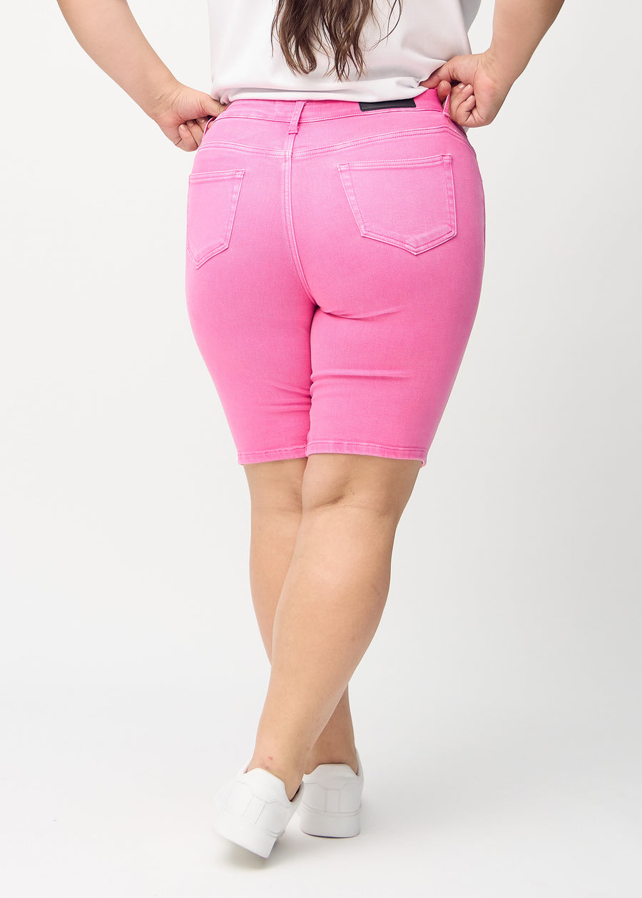 Ljusrosa skinny middle shorts sedda bakifrån på en plus size-modell, så att man kan se hela produkten.