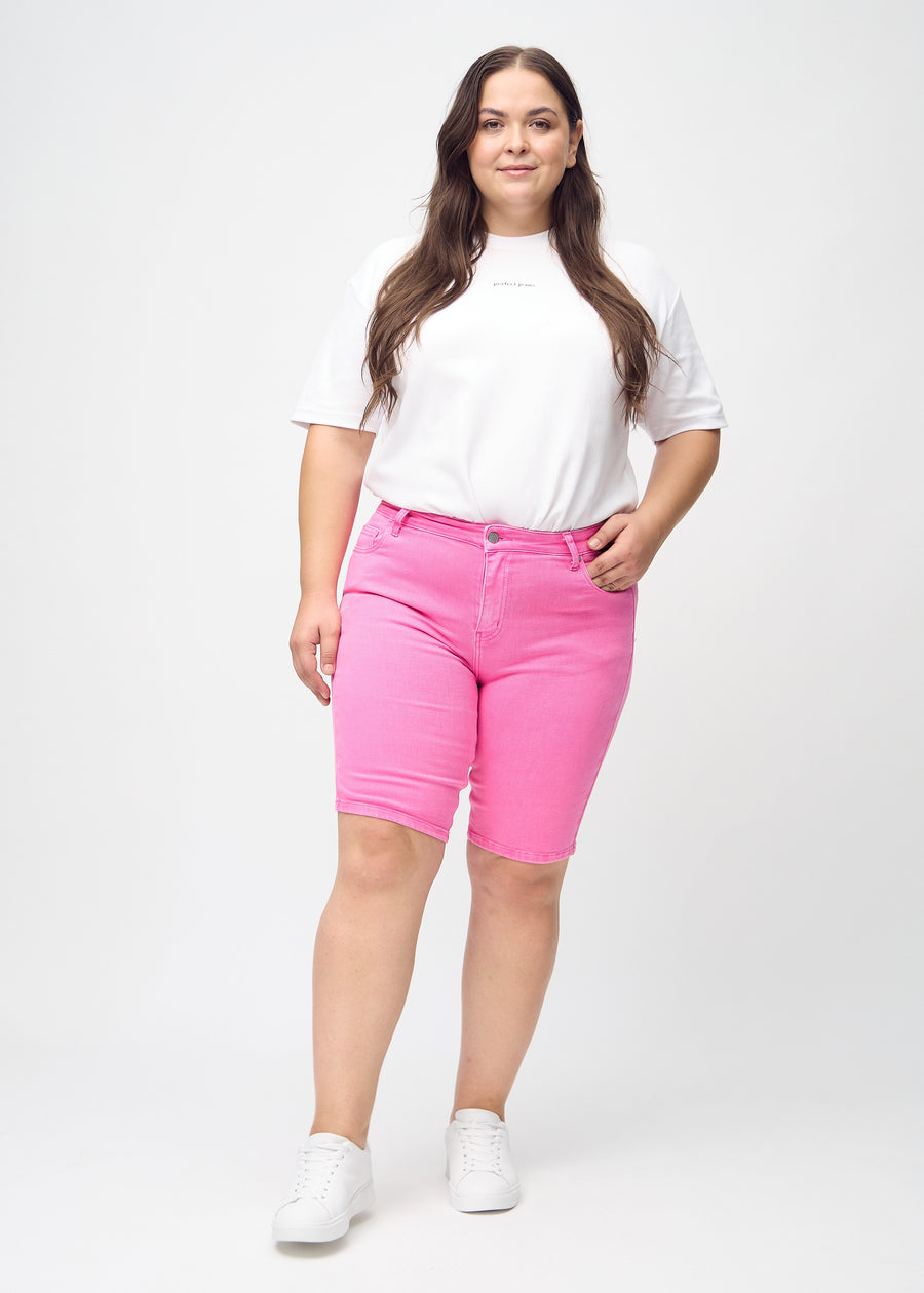 Helbild av en plus size-modell i ljusrosa skinny middle shorts.