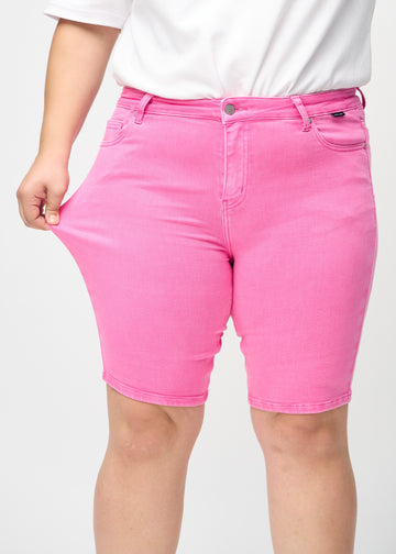 Plus size-modellen sträcker ut shortsen vid låret för att visa stretch.