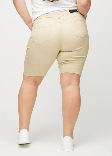 Beige skinny middle shorts sedda bakifrån på en plus-size-modell, så att hela produkten syns.