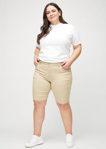 Helbild av en plus-size-modell i beige skinny middle shorts.