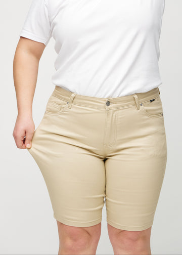 Plus-size-modellen sträcker shortsens tyg vid låret för att visa stretch.