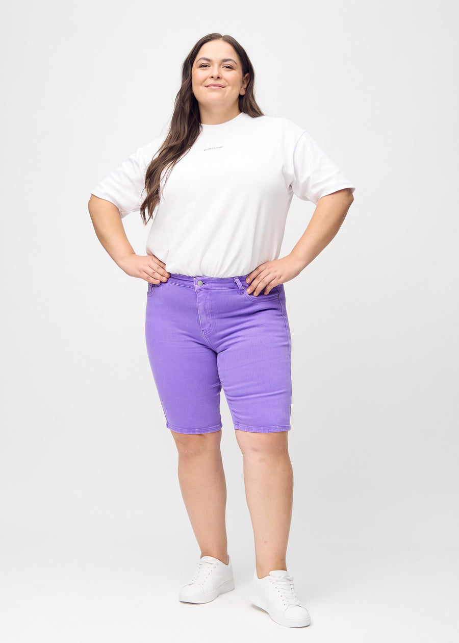 Helbild av en plus size-modell i lila skinny middle shorts.