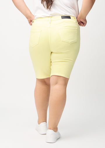 Ljusgula skinny middle shorts sedda bakifrån på en plus size-modell, så att man kan se hela produkten.