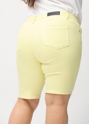 Ljusgula skinny middle shorts sedda bakifrån på nära håll på en plus size-modell för att visa detaljer.