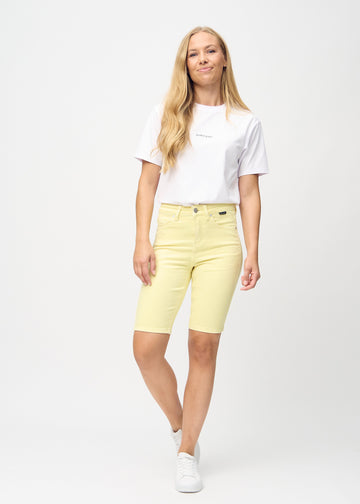 Helbild av modell i ljusgula skinny middle shorts.