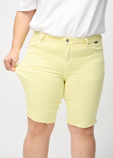 Plus size-modellen sträcker ut shortsen vid låret för att visa stretch.