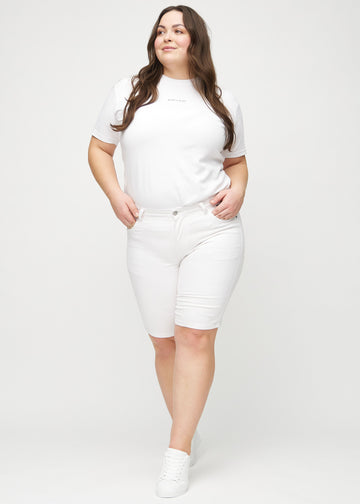 Helbild av en plus-size-modell i vita skinny middle shorts.