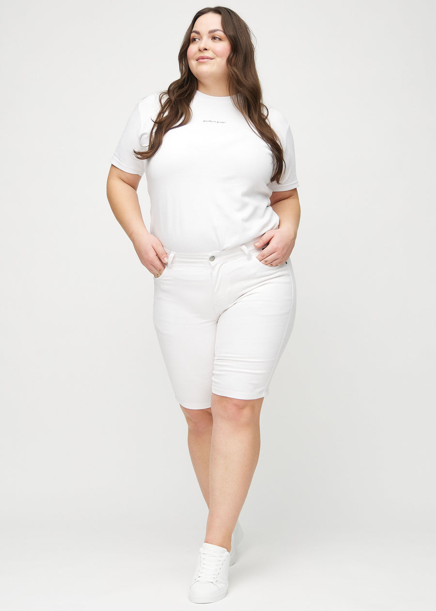 Helbild av en plus-size-modell i vita skinny middle shorts.