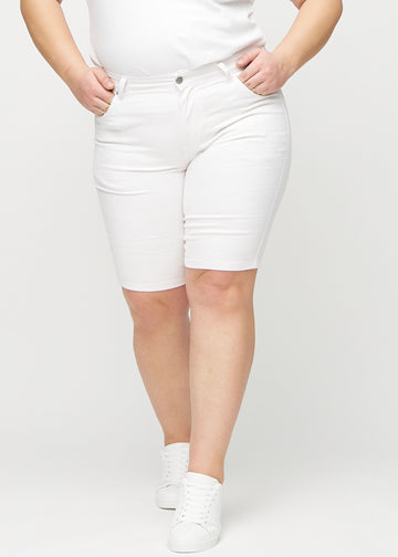 Vita skinny middle shorts, modellnamn Marguerites, som sitter tight över låret och slutar precis ovanför knät på en plus-size-modell, sedda framifrån.