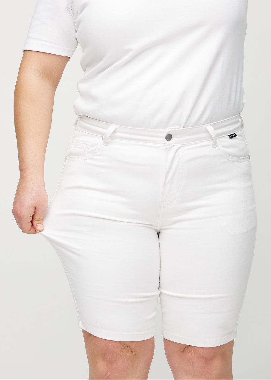 Plus-size-modellen drar ut shortsen vid låret för att visa stretch.