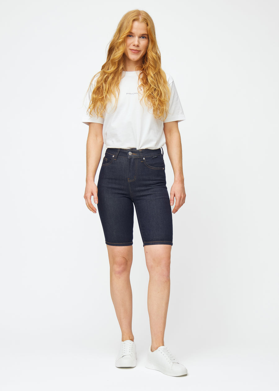 Helbild av modell i mörkblå denimshorts för dam i färgen Midnights med skinny passform.