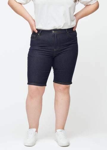 Mörkblå denimshorts för dam i färgen Midnights med skinny passform sett framifrån på plus-size modell.