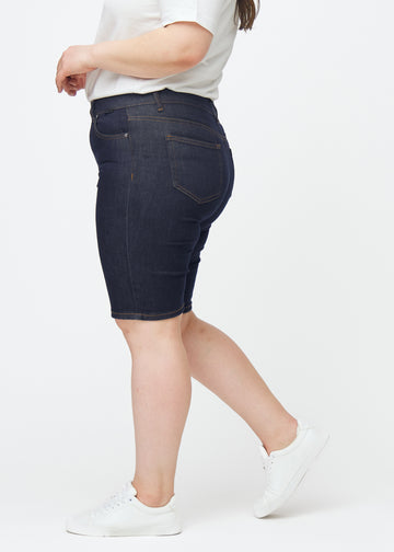 Mörkblå denimshorts för dam i färgen Midnights med skinny passform sett från sidan på plus-size modell.