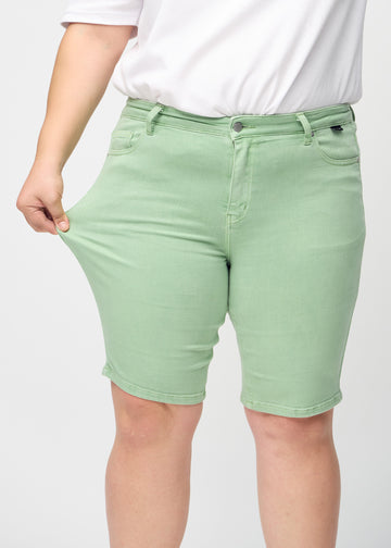 Plus-size-modellen sträcker ut shortsen vid låret för att visa stretch.