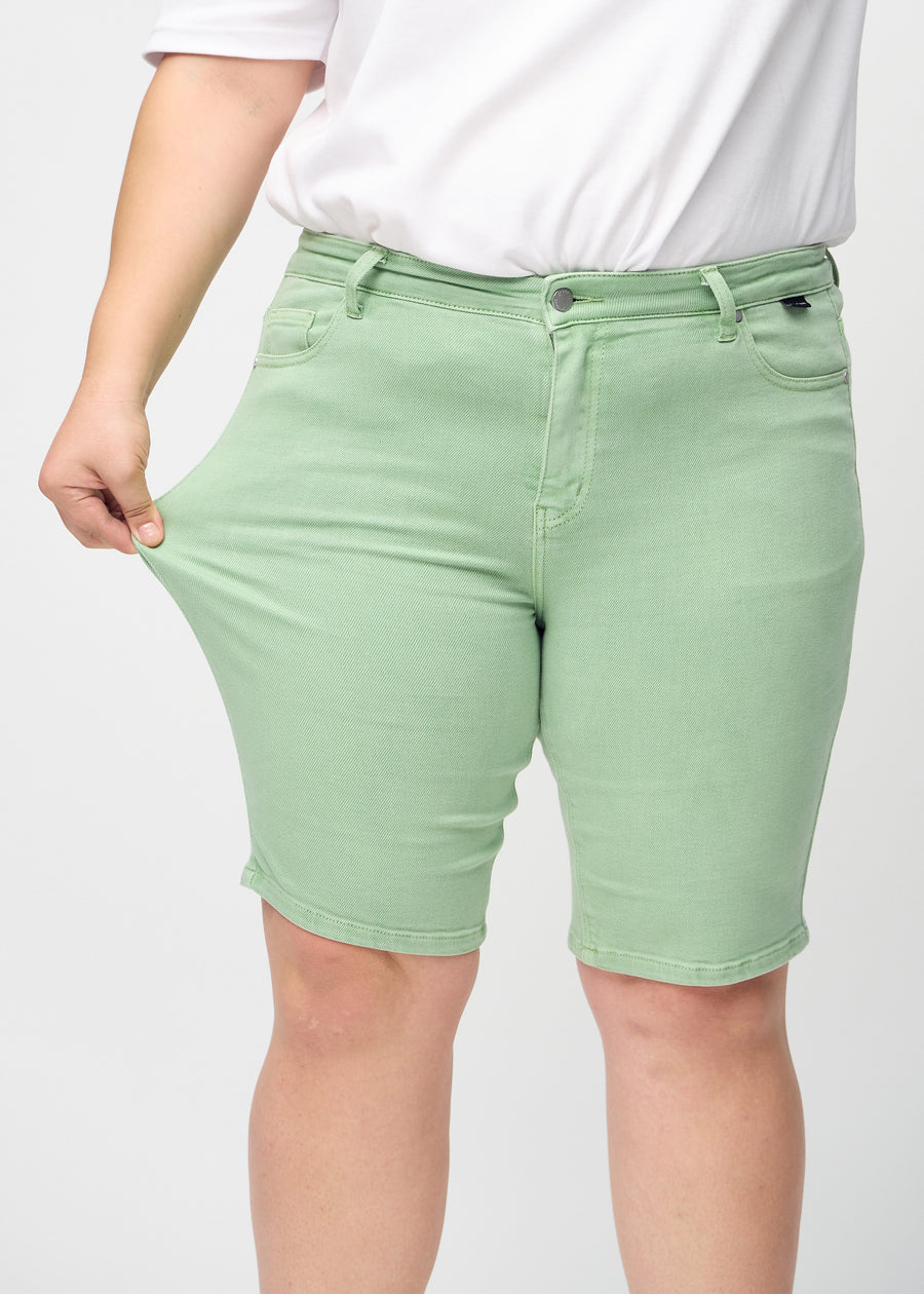 Plus-size-modellen sträcker ut shortsen vid låret för att visa stretch.