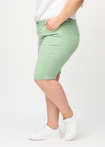 Ljusgröna skinny middle shorts sedda från sidan på en plus-size-modell.