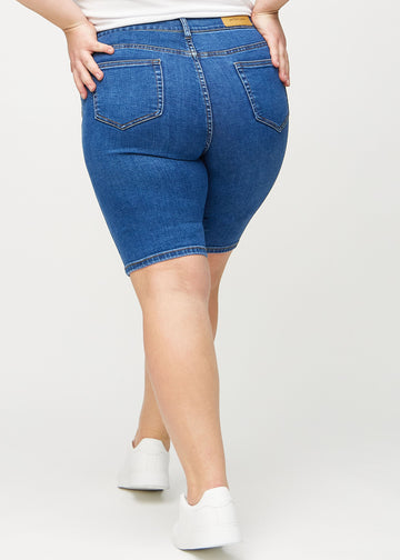 Mörk denim skinny middle shorts sedda bakifrån på en plus-size-modell, så att man kan se hela produkten.
