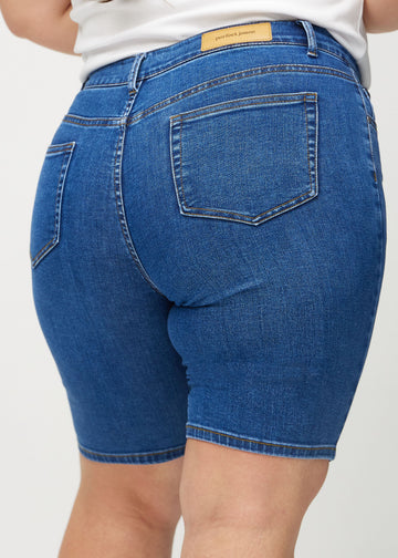 Mörk denim skinny middle shorts sedda bakifrån på nära håll på en plus-size-modell för att visa detaljer.