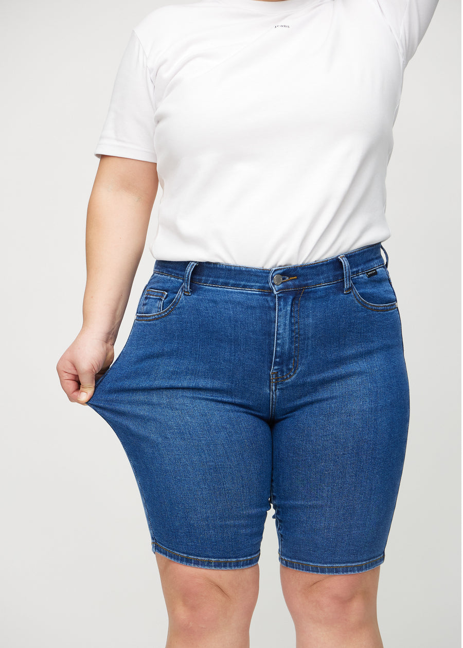 Plus-size-modellen drar i shortsen vid låret för att visa stretch.