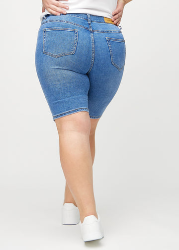 Denim skinny middle shorts sedda bakifrån på en plus size-modell, så att man kan se hela produkten.