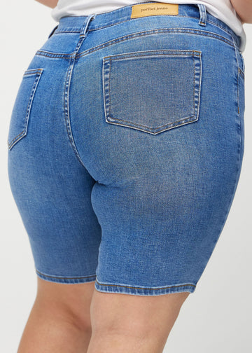 Denim skinny middle shorts sedda bakifrån i närbild på en plus size-modell för att visa detaljer.