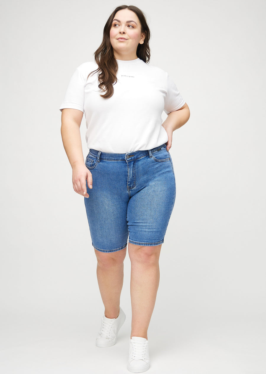 Helbild av en plus size-modell i denim skinny middle shorts.