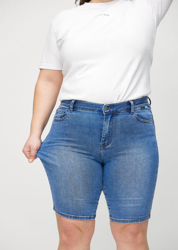 Plus size-modellen drar ut shortsen vid låret för att visa stretch.