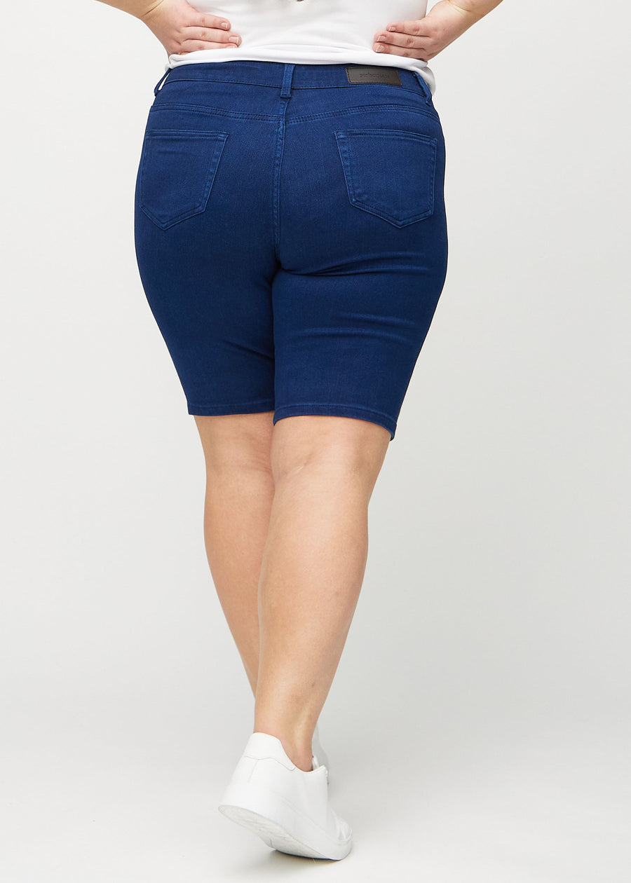 Mörkblå skinny middle shorts sedda bakifrån på en plus-size-modell, så att man kan se hela produkten.