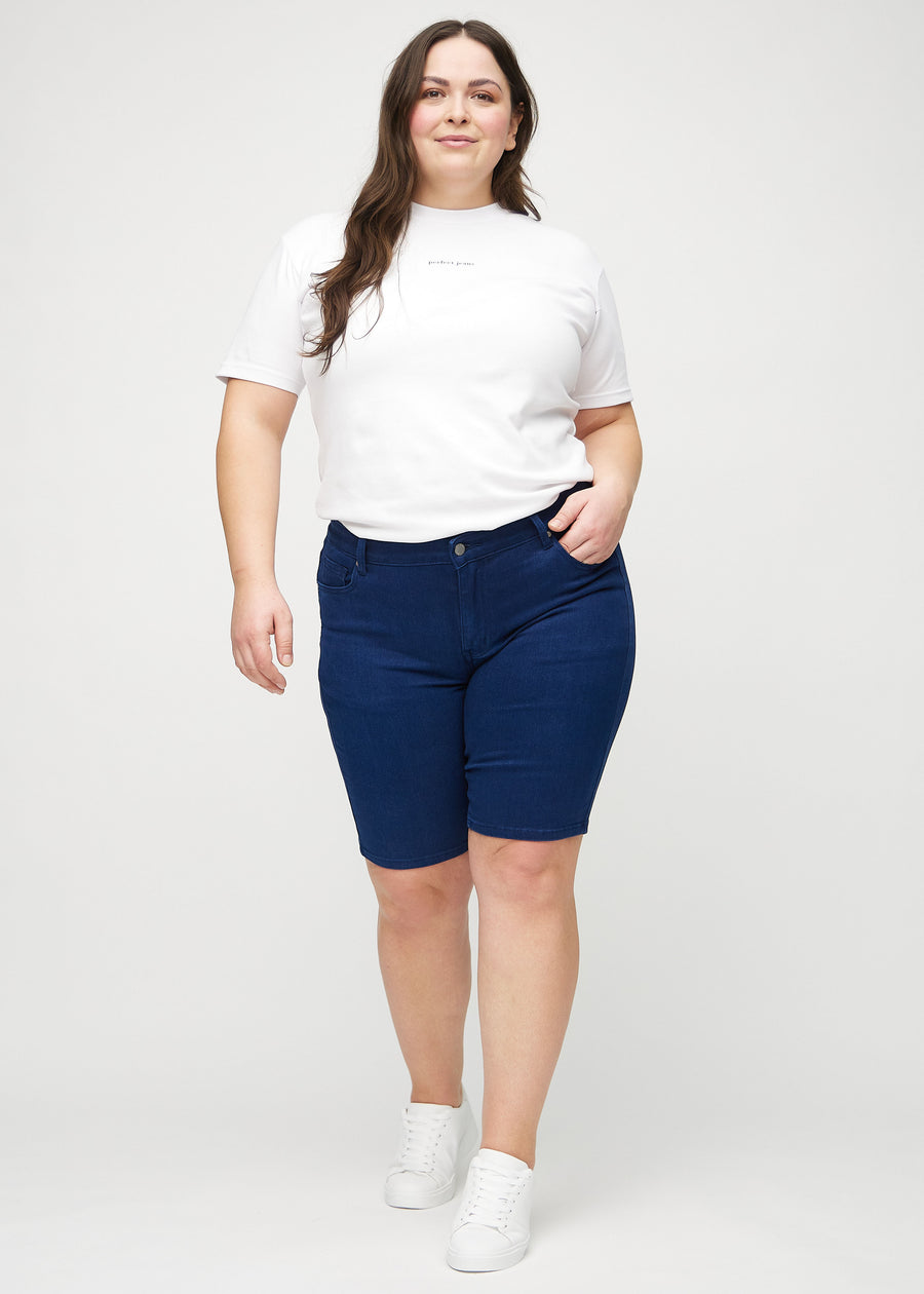 Helbild av en plus-size-modell i mörkblå skinny middle shorts.