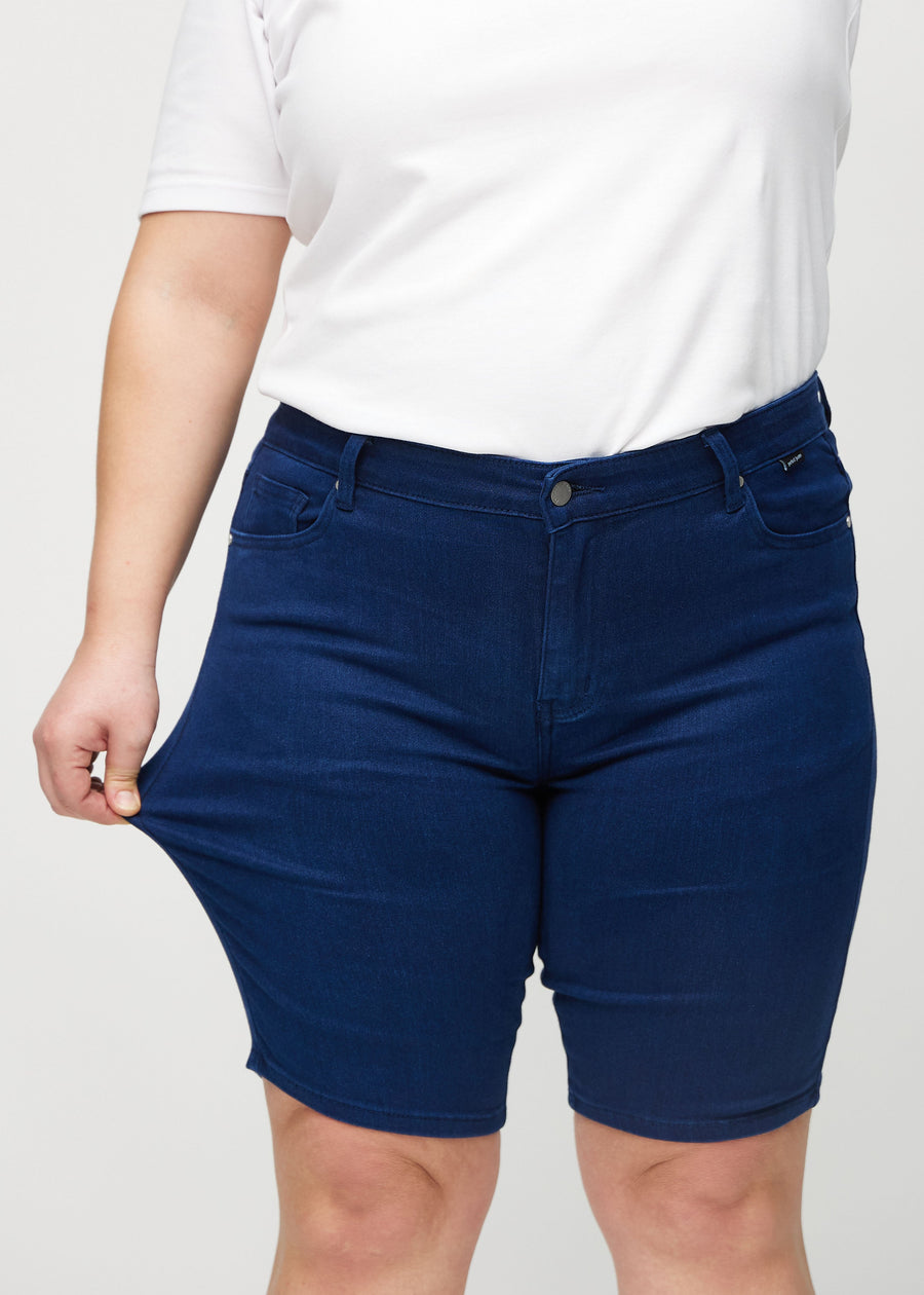 Plus-size-modellen drar ut shortsen vid låret för att visa stretch.