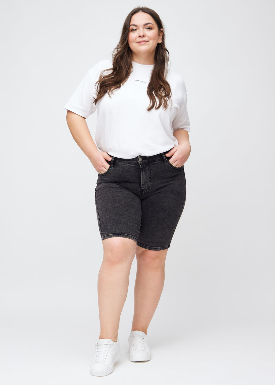 Helbild av en plus size-modell i mörkgrå denim skinny middle shorts.