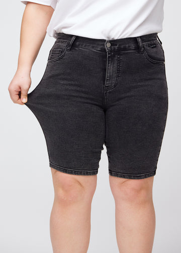 Plus size-modellen drar ut shortsen vid låret för att visa stretch.