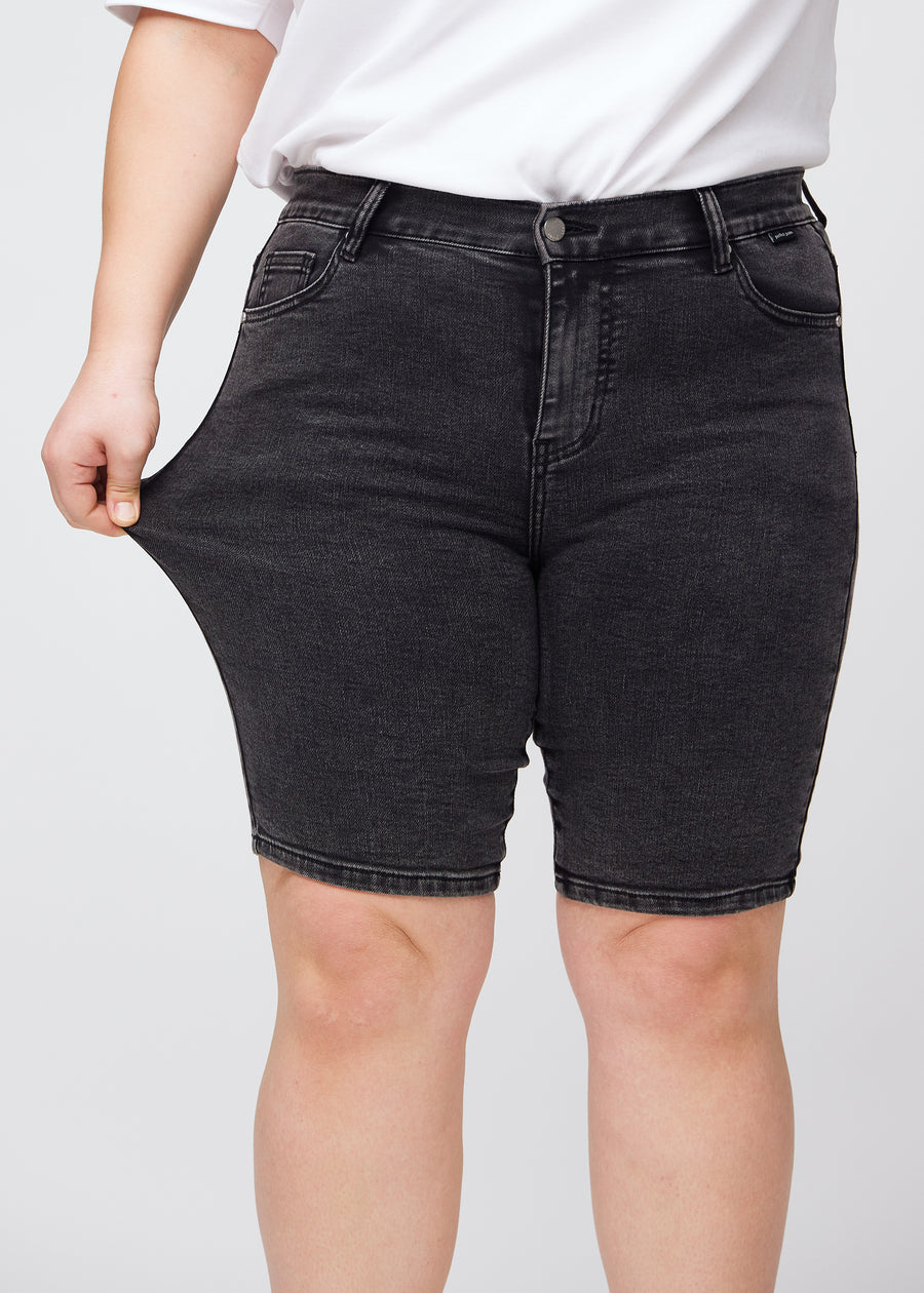 Plus size-modellen drar ut shortsen vid låret för att visa stretch.
