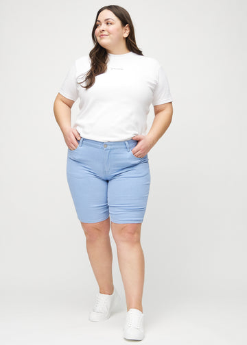 Helbild av en plus-size-modell i ljusblå skinny middle shorts.